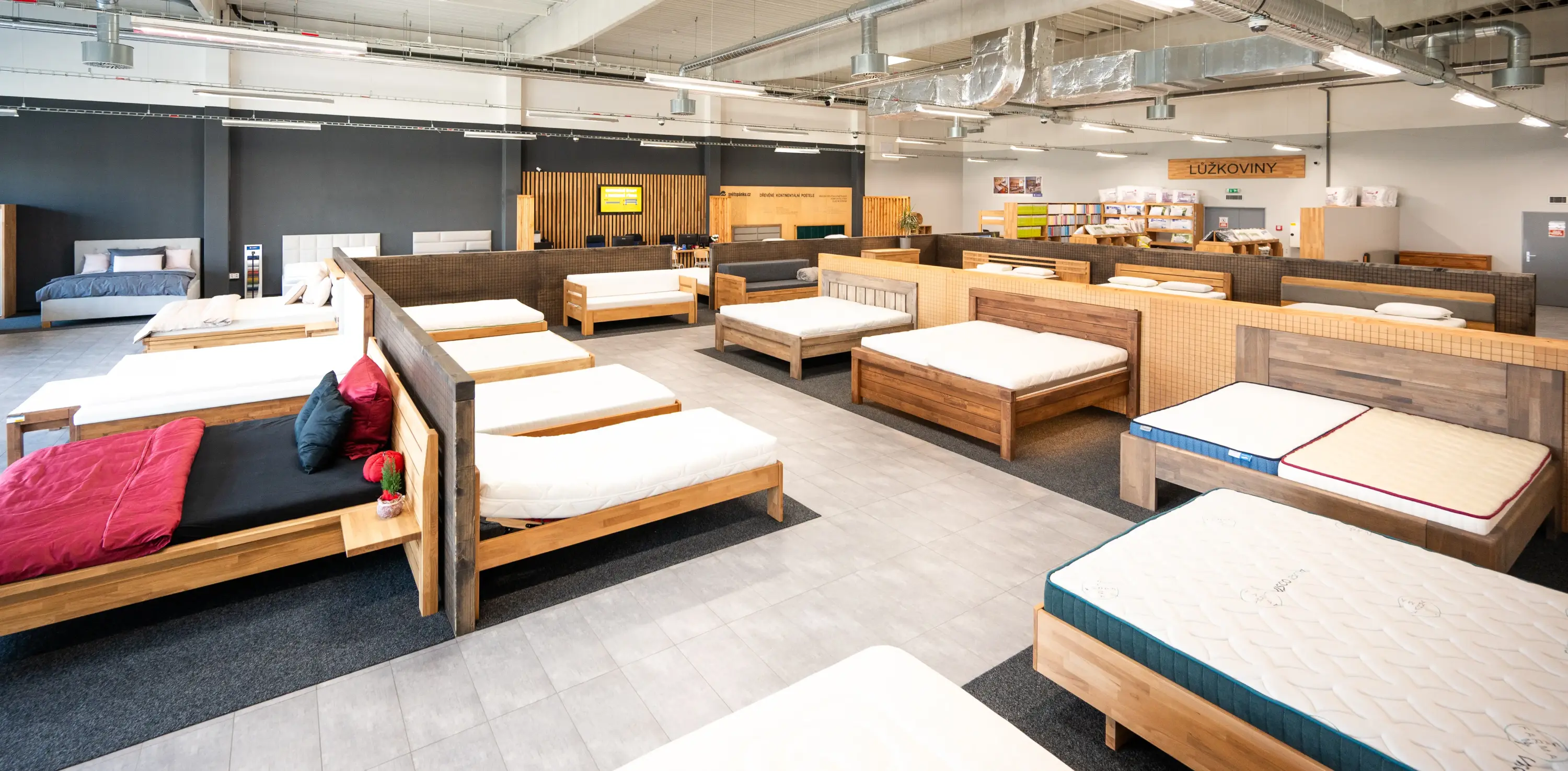 Prodejna světspánku – Olomouc, několik vystavených dřevěných postelí a matrací v moderním showroomu s dřevěnými příčkami